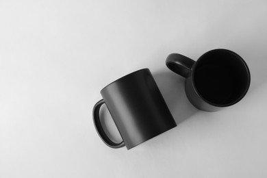 Photo of Two blank black mugs on white background, top view. Mockup for design