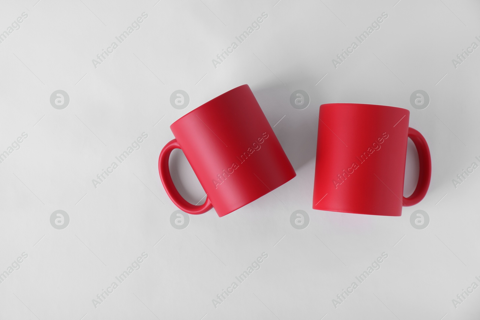 Photo of Two blank red mugs on white background, top view. Mockup for design