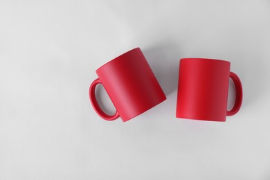 Photo of Two blank red mugs on white background, top view. Mockup for design