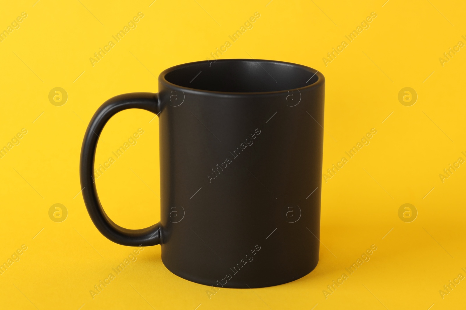 Photo of One blank black mug on yellow background. Mockup for design