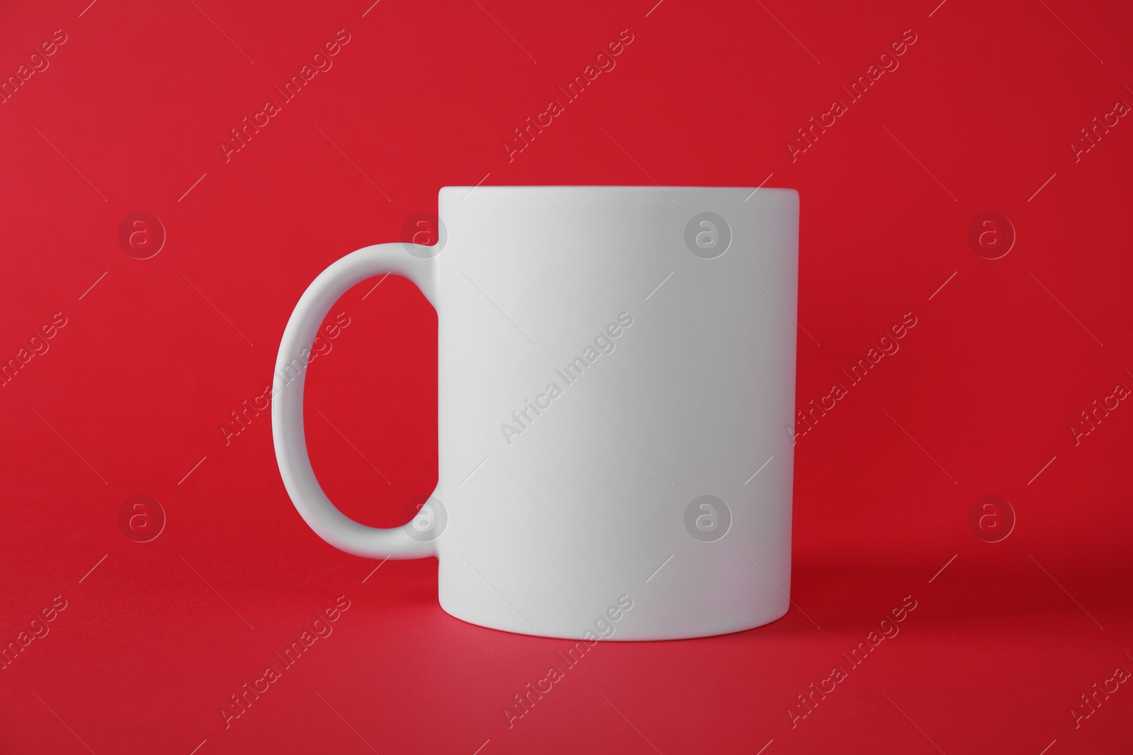 Photo of One blank white mug on red background. Mockup for design