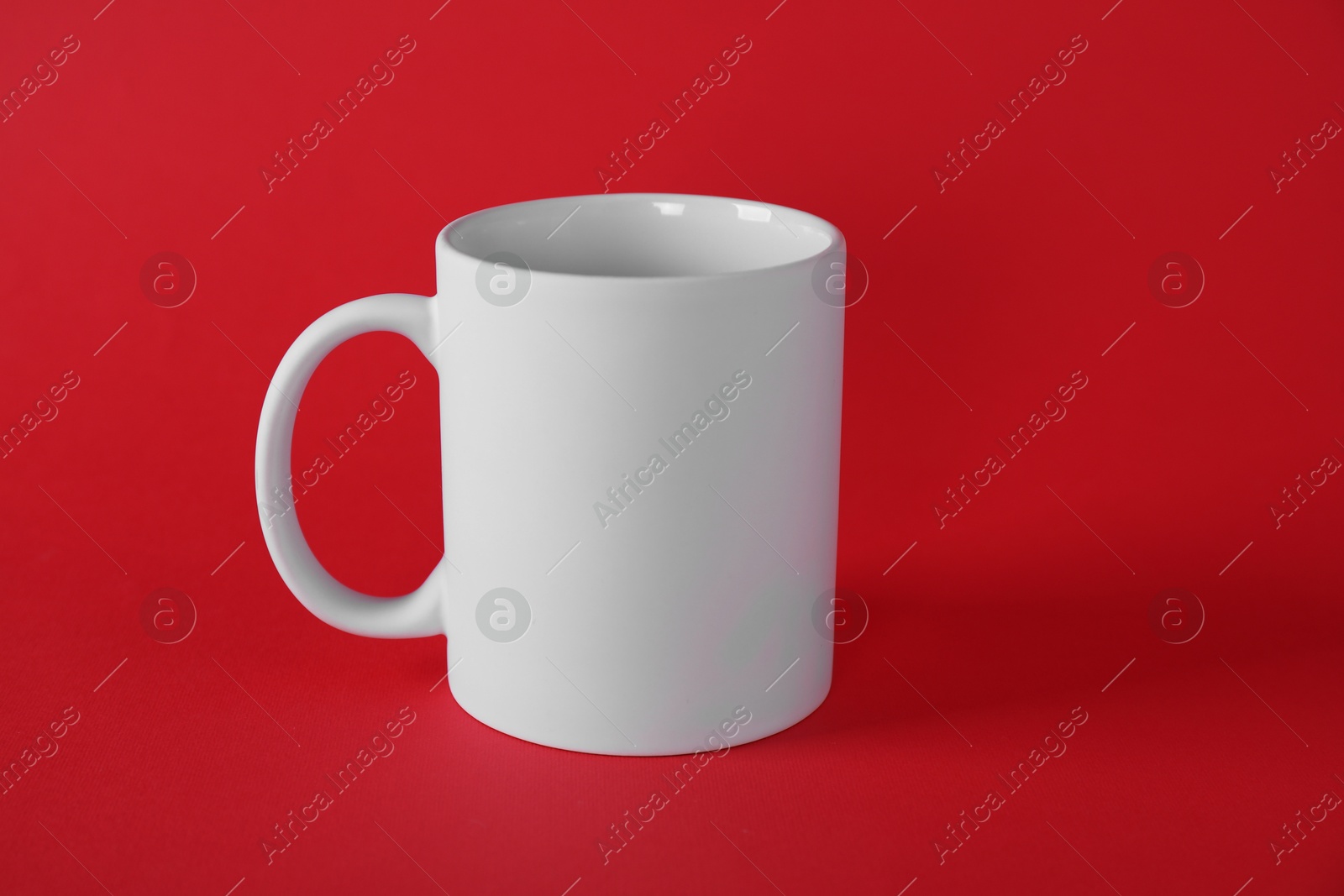 Photo of One blank white mug on red background. Mockup for design