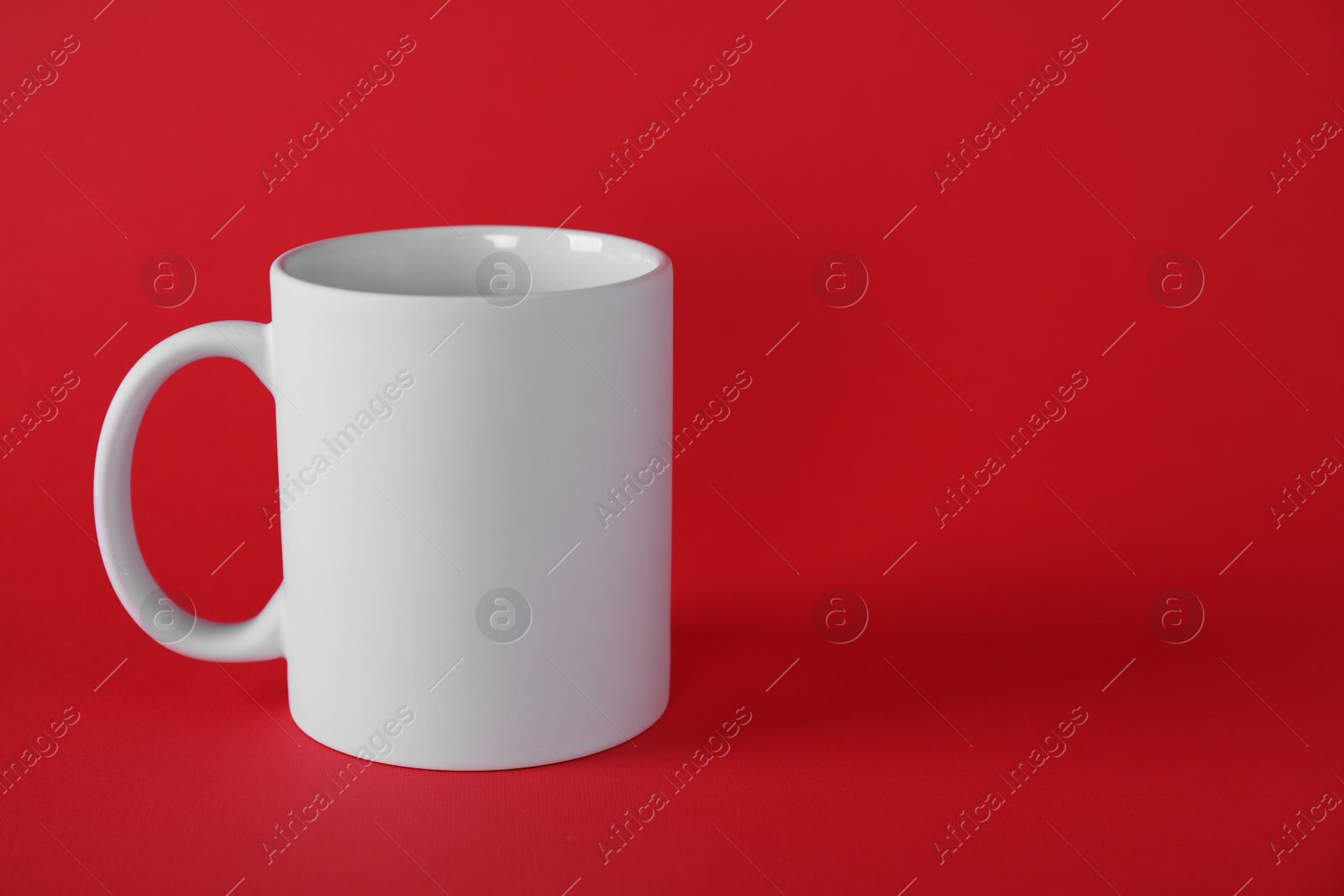 Photo of One blank white mug on red background. Mockup for design