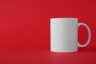 Photo of One blank white mug on red background. Mockup for design