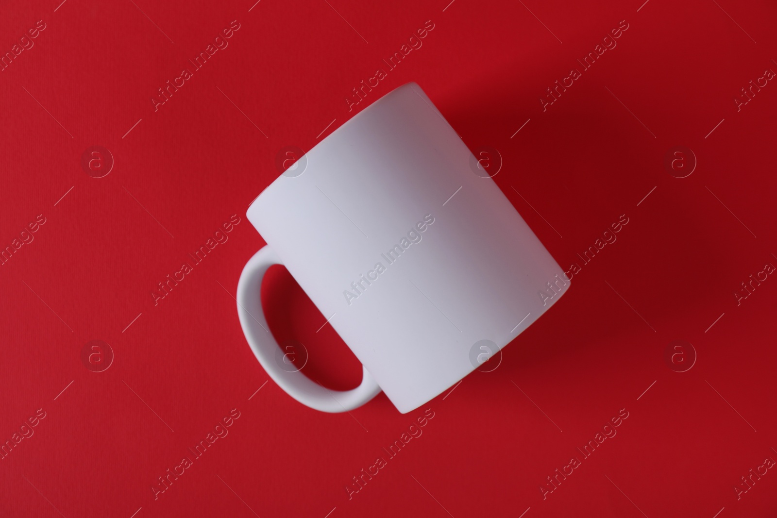 Photo of One blank white mug on red background. Mockup for design