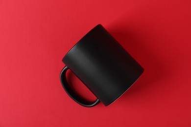 Photo of One blank black mug on red background. Mockup for design