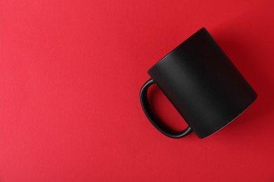 Photo of One blank black mug on red background. Mockup for design