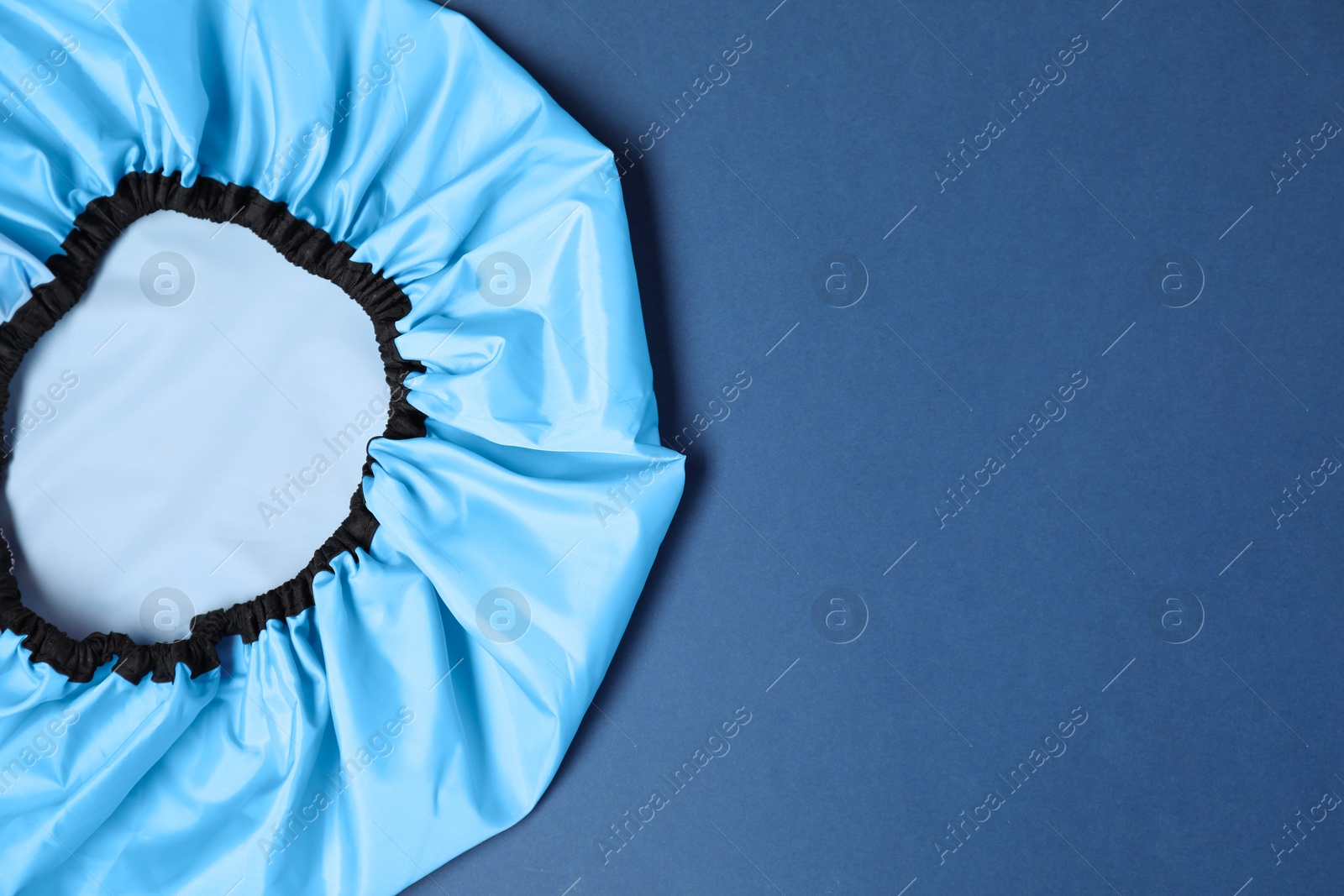 Photo of One shower cap on blue background, top view. Space for text