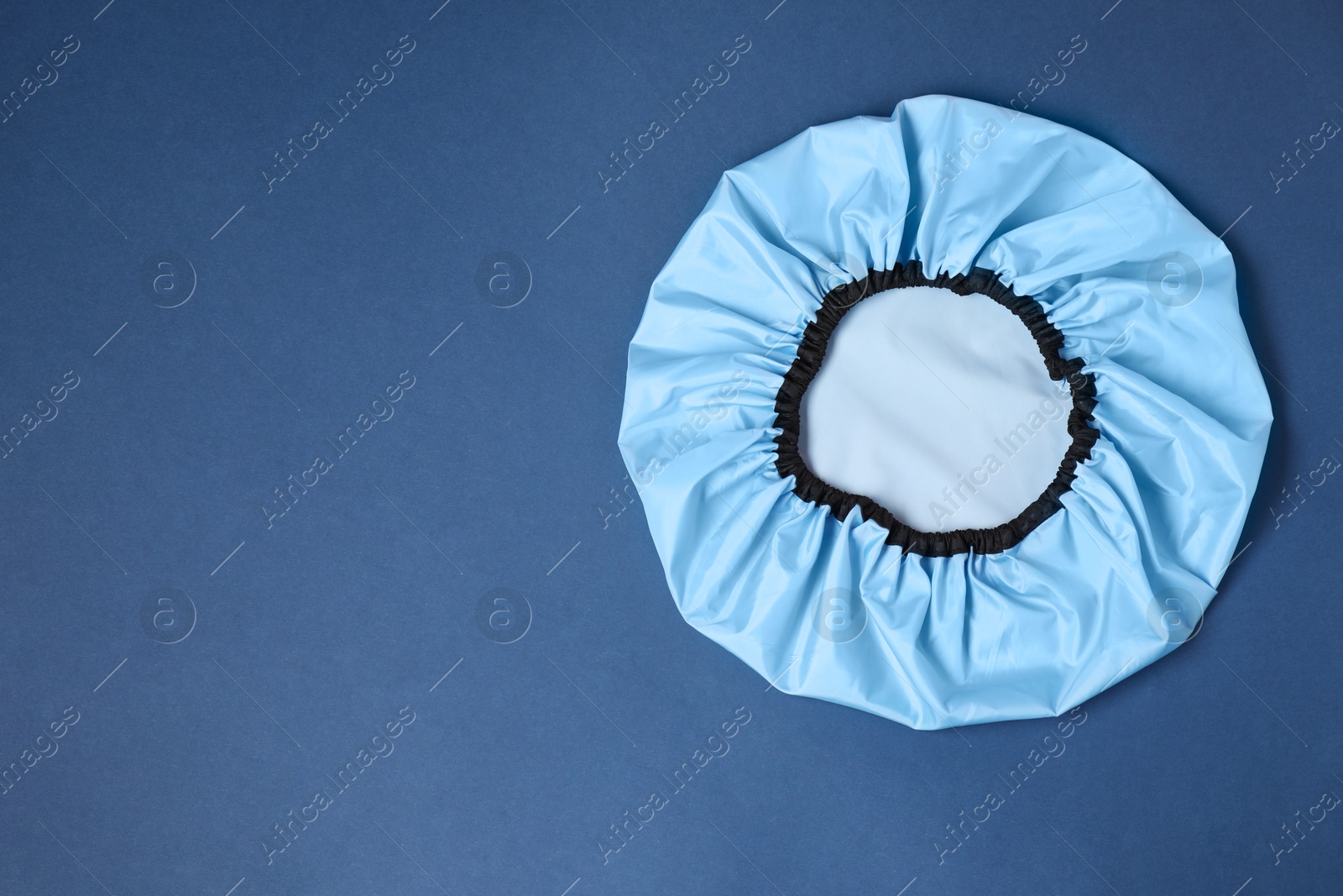 Photo of One shower cap on blue background, top view. Space for text