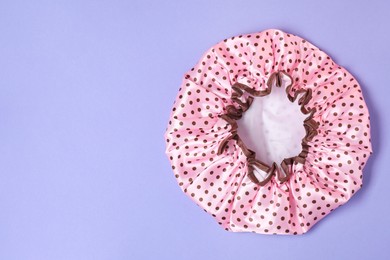 Photo of One shower cap on lilac background, top view. Space for text