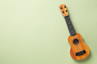 Photo of One ukulele on green background, top view. Space for text