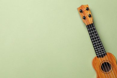 Photo of One ukulele on green background, top view. Space for text