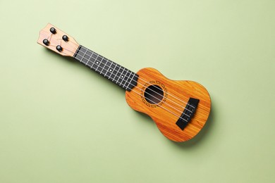 Photo of One ukulele on green background, top view