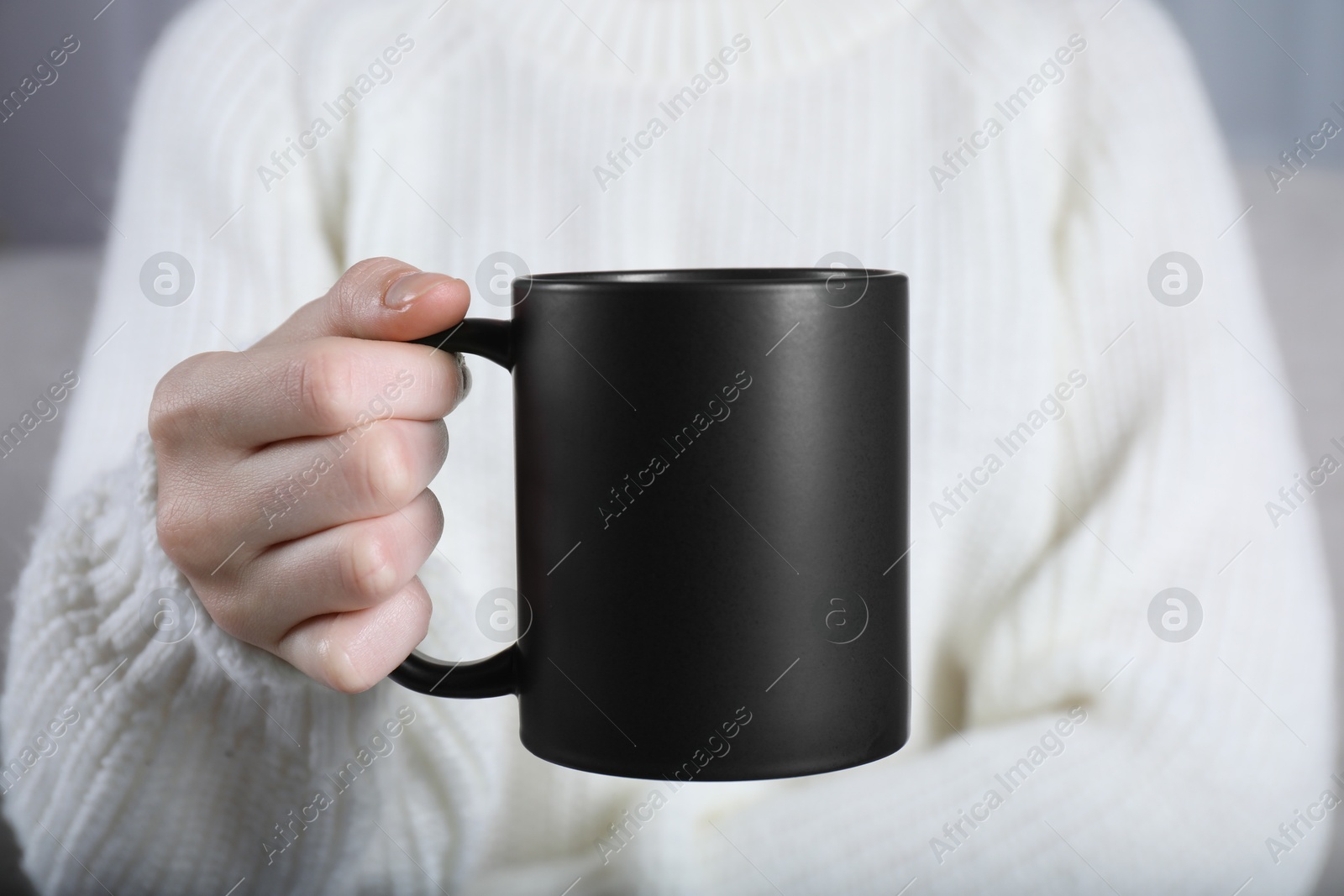 Photo of Woman holding blank black ceramic mug, closeup. Mockup for design