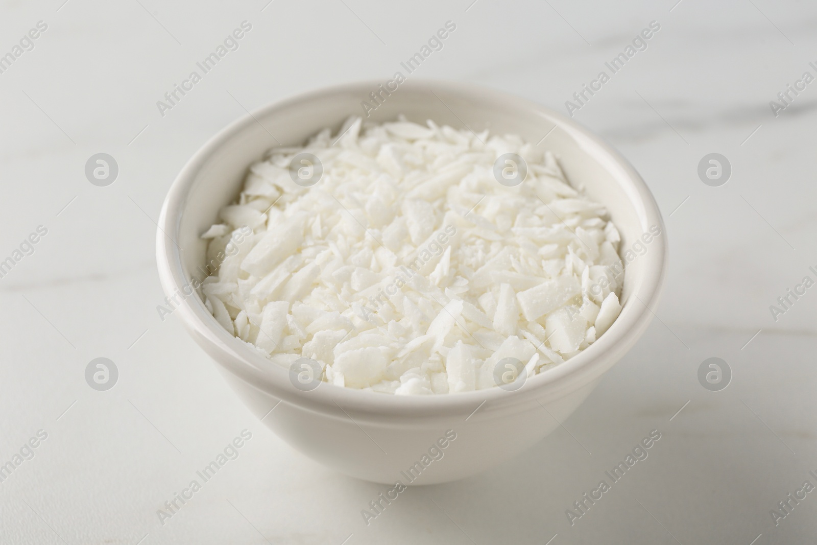 Photo of Soy wax in bowl on white marble table