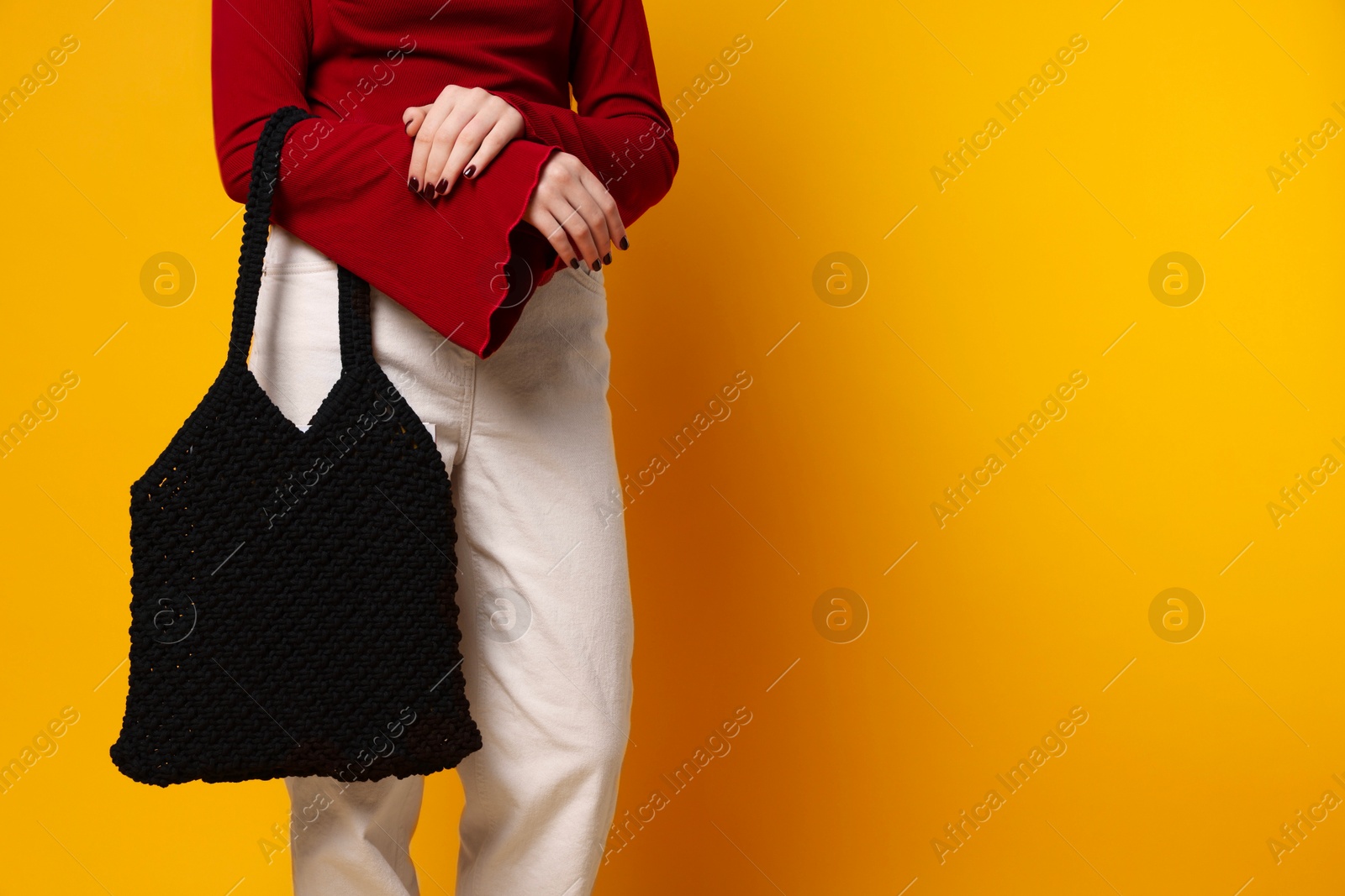 Photo of Teenage girl with handmade macrame bag on yellow background, closeup. Space for text