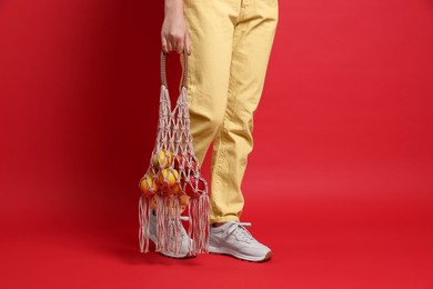 Photo of Teenage girl with handmade macrame bag on red background, closeup