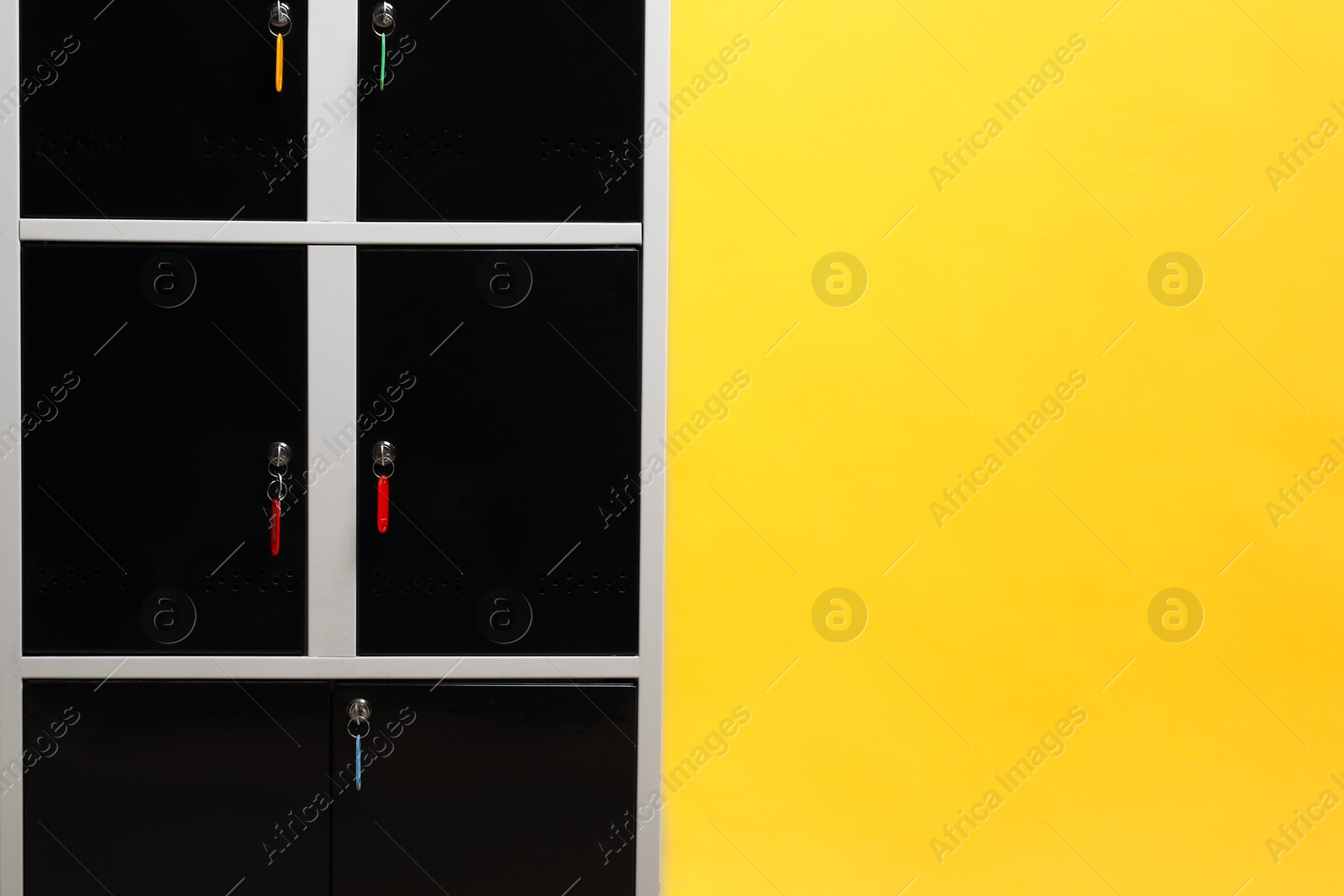 Photo of Modern lockers with keys on orange background, space for text