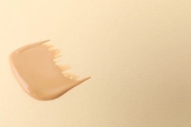 Photo of Sample of foundation on beige background, space for text