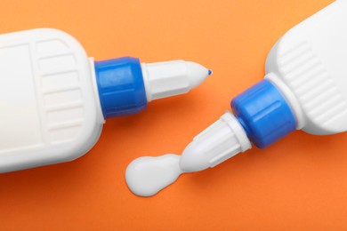 Photo of Bottles of glue on orange background, top view