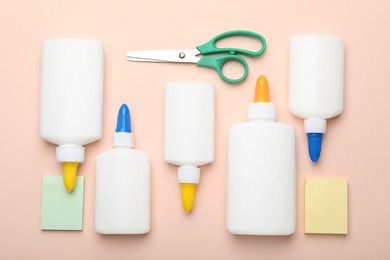 Photo of Bottles of glue, scissors and notes on beige background, flat lay