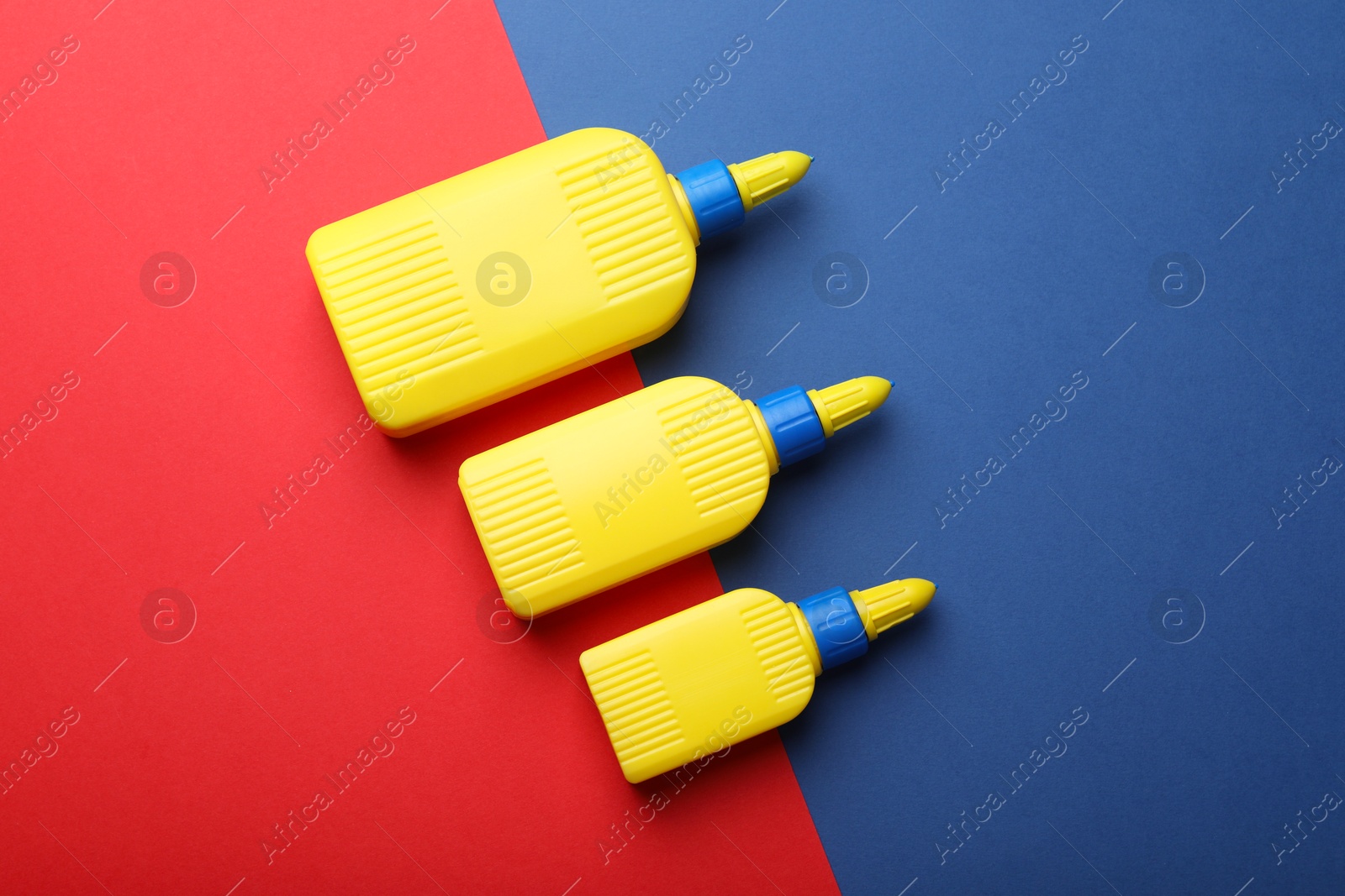 Photo of Bottles of glue on color background, flat lay