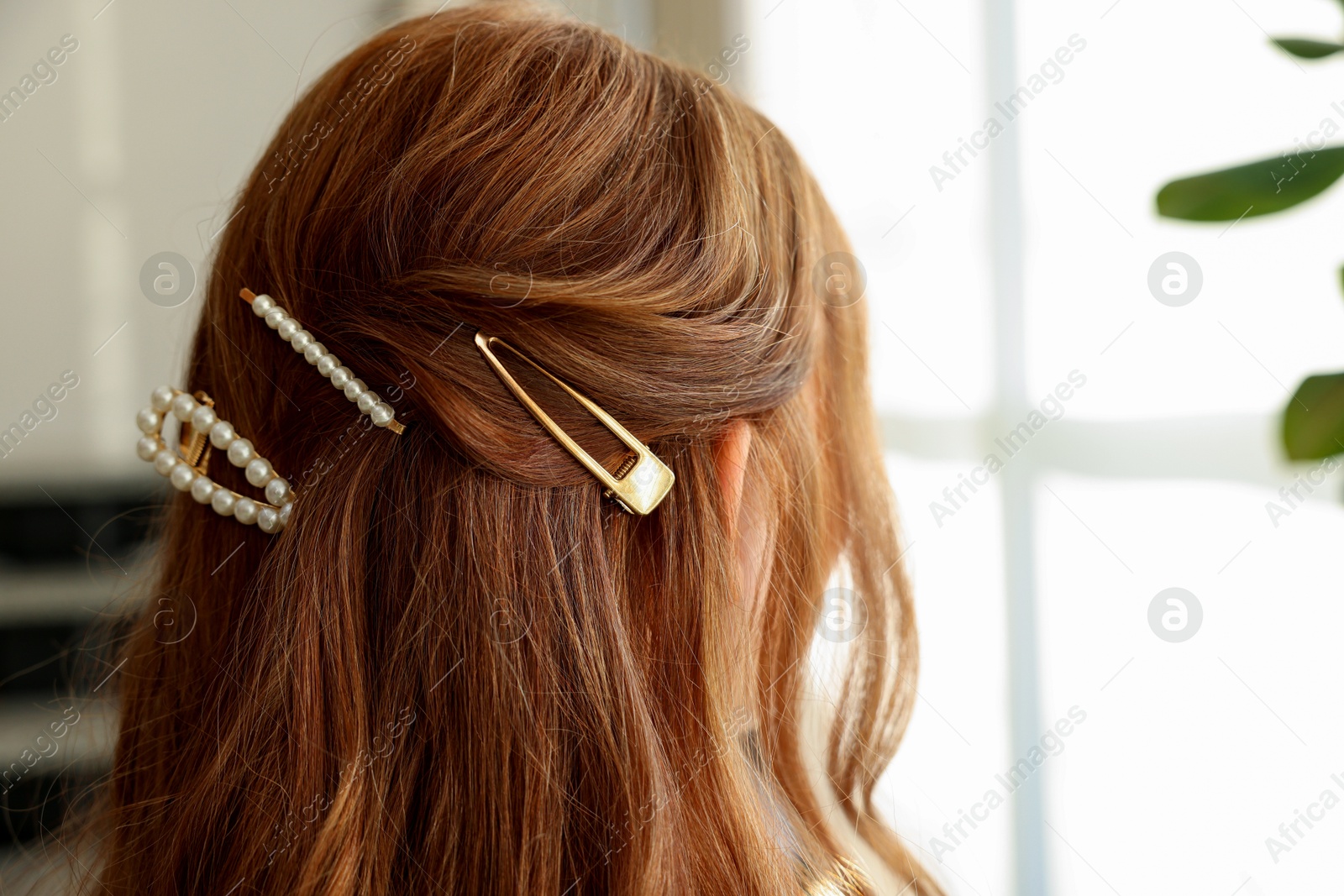 Photo of Teenage girl with stylish hair clips indoors, back view