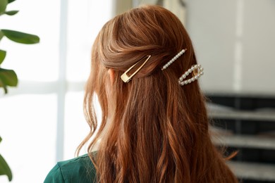 Photo of Teenage girl with stylish hair clips indoors, back view