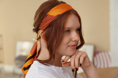 Photo of Red-haired teenage girl with stylish bandana indoors