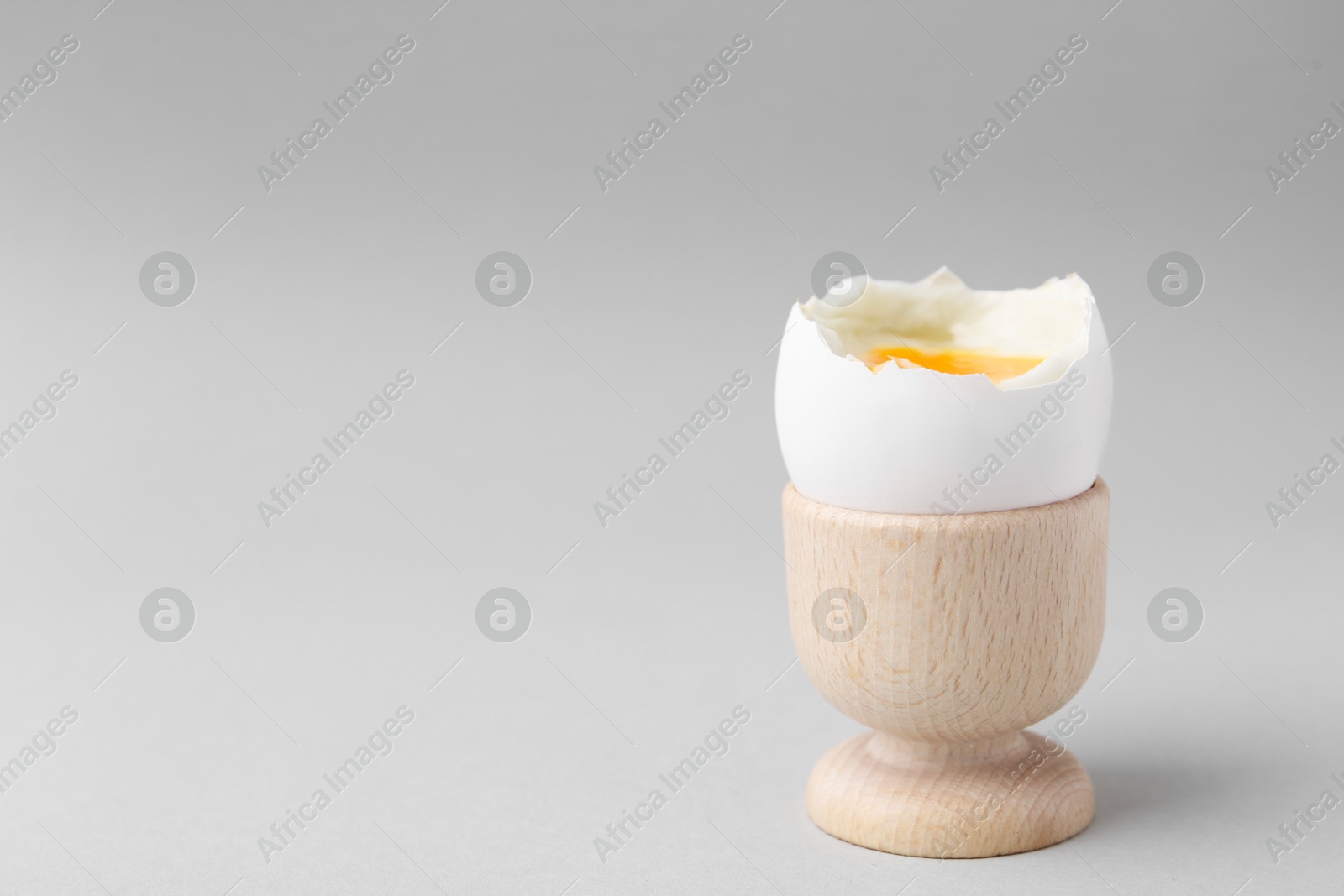 Photo of Soft boiled egg in cup on light grey background, space for text