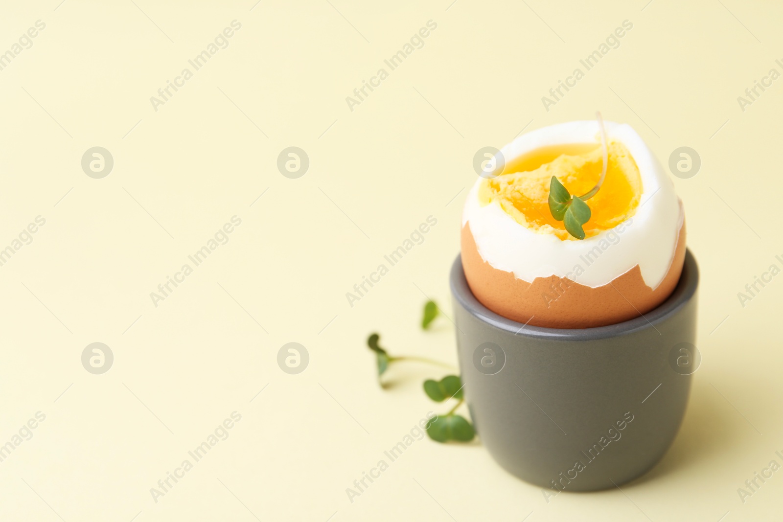 Photo of Soft boiled egg in eggcup on beige background, closeup. Space for text