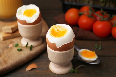 Photo of Soft boiled eggs and tomatoes on wooden table, selective focus