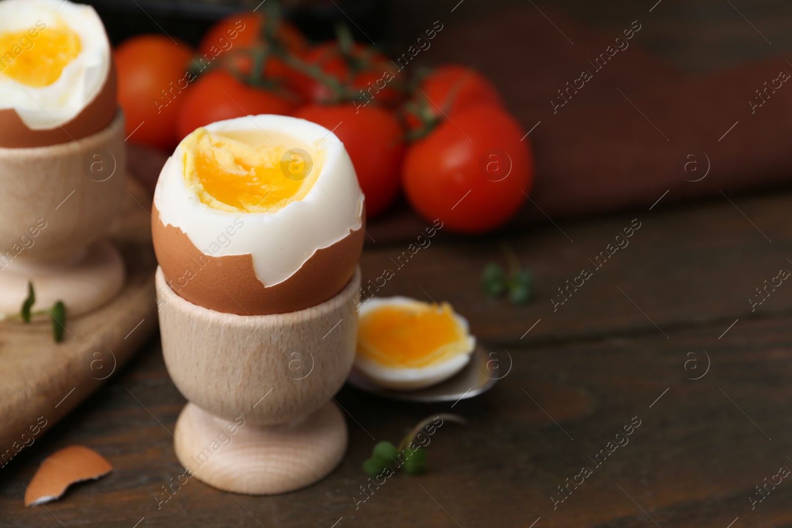 Photo of Soft boiled eggs and tomatoes on wooden table, selective focus. Space for text