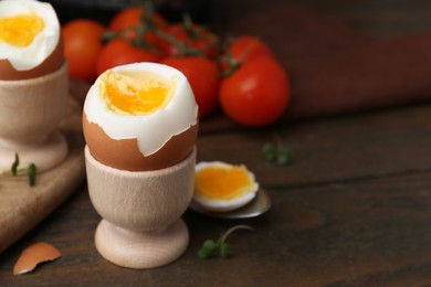 Photo of Soft boiled eggs and tomatoes on wooden table, selective focus. Space for text