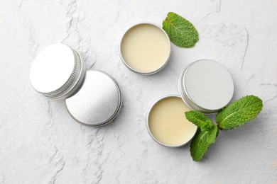 Photo of Mint lip balms and green leaves on beige textured background, flat lay. Cosmetic product