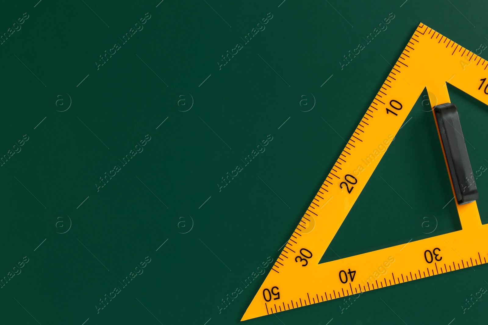 Photo of One triangle ruler on green chalkboard, top view. Space for text