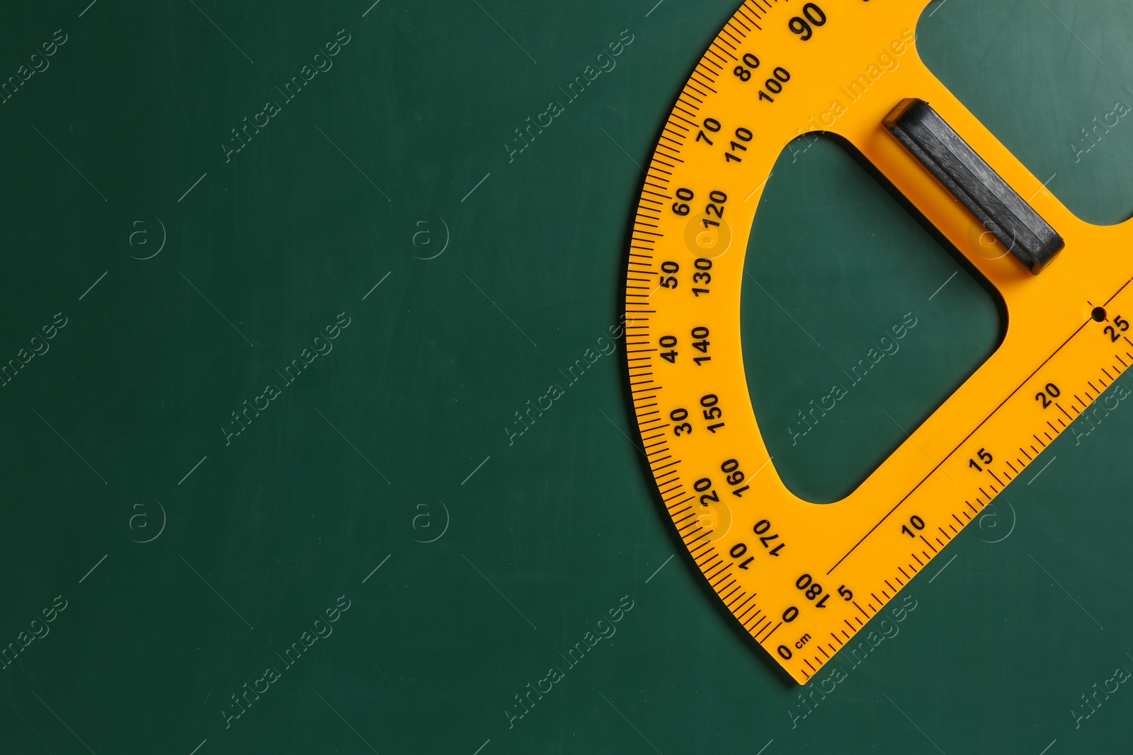 Photo of Protractor ruler on green chalkboard, top view. Space for text