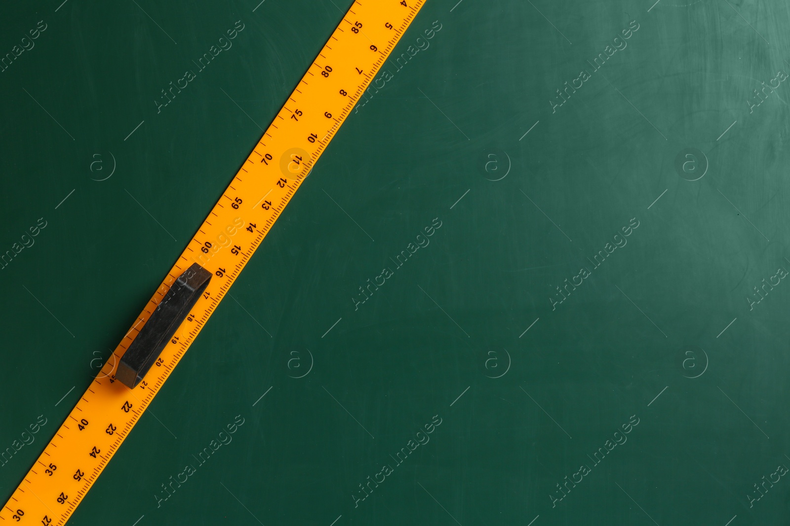 Photo of One ruler on green chalkboard, top view. Space for text