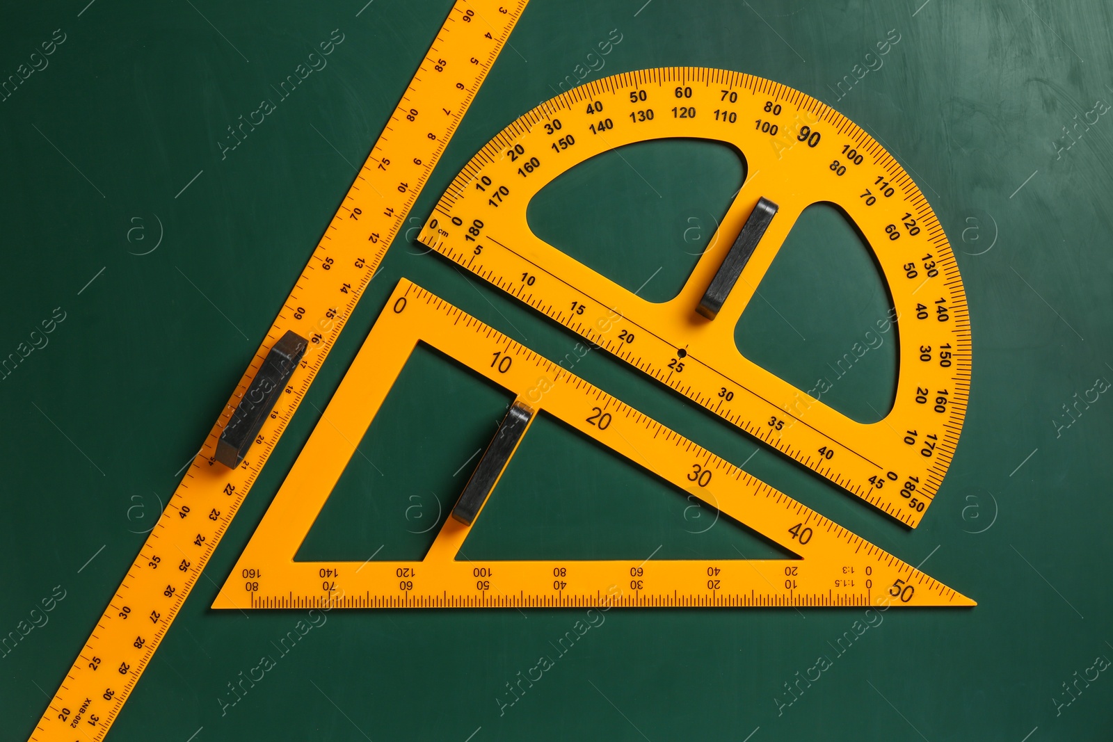 Photo of Triangle, protractor and ruler on green chalkboard, flat lay