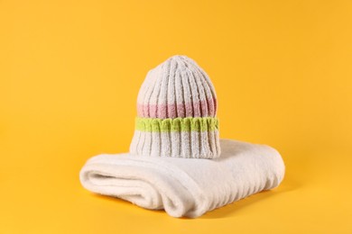 Photo of Stylish knitted hat and warm scarf on yellow background