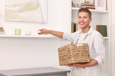 Photo of Smiling decorator arranging decor onto shelf at home