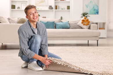 Photo of Smiling decorator placing beige carpet indoors. Space for text