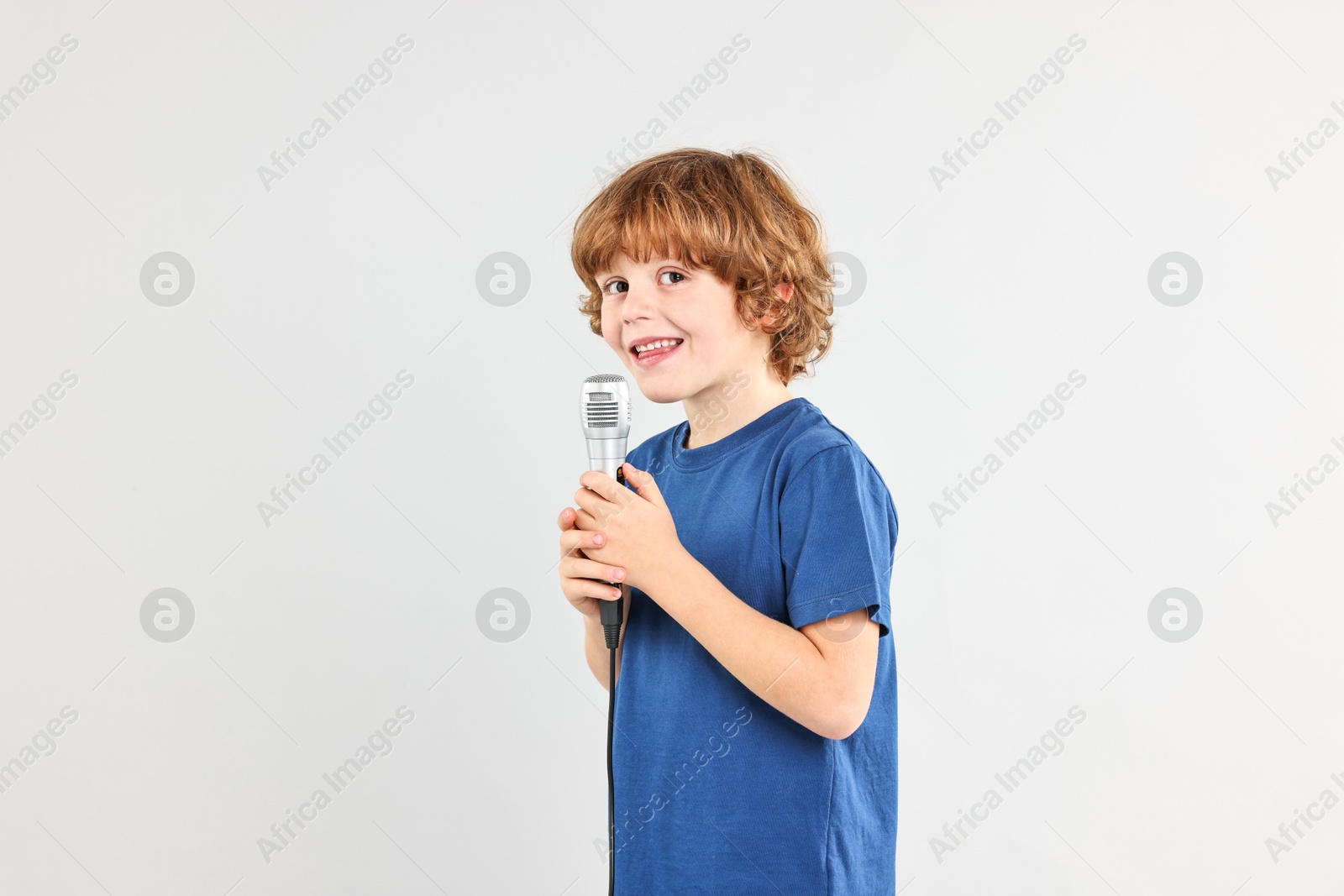 Photo of Little boy with microphone on light grey background