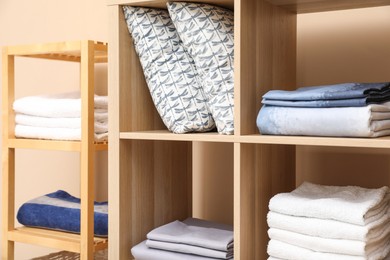 Photo of Different home textile on shelving units indoors, closeup