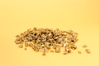 Photo of Shiny gold nuggets on yellow background, closeup