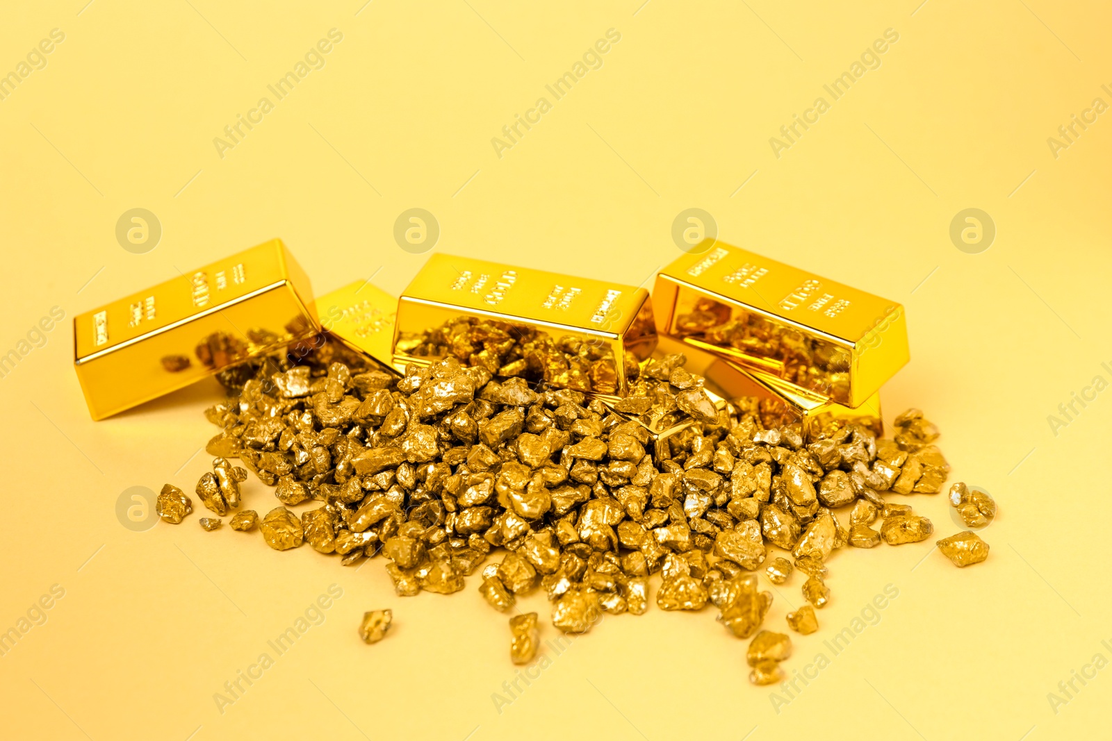 Photo of Gold nuggets and bars on yellow background