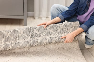 Photo of Female decorator rolling out carpet indoors, closeup