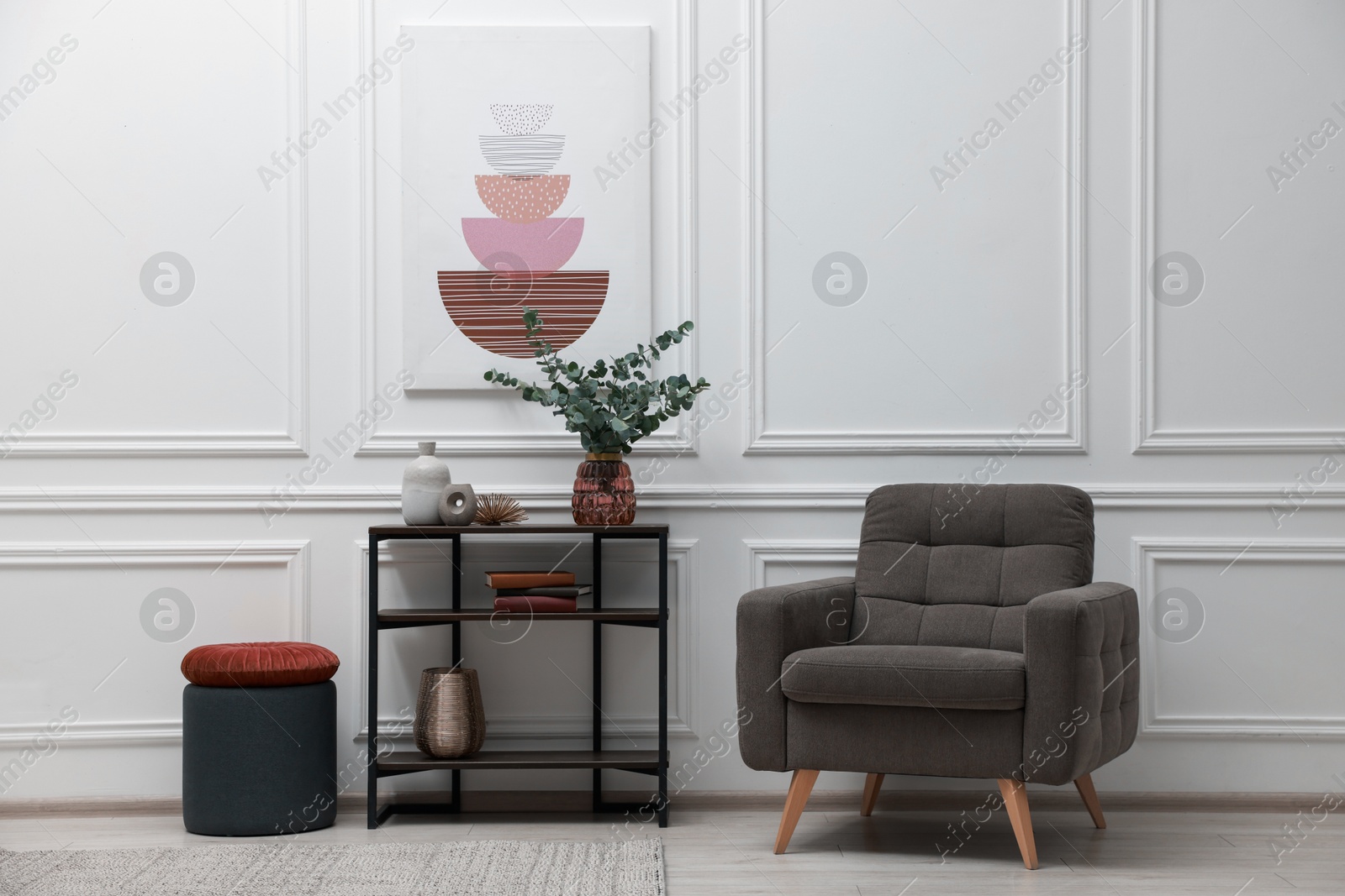 Photo of Console table with decor and armchair near white wall in room. Interior design