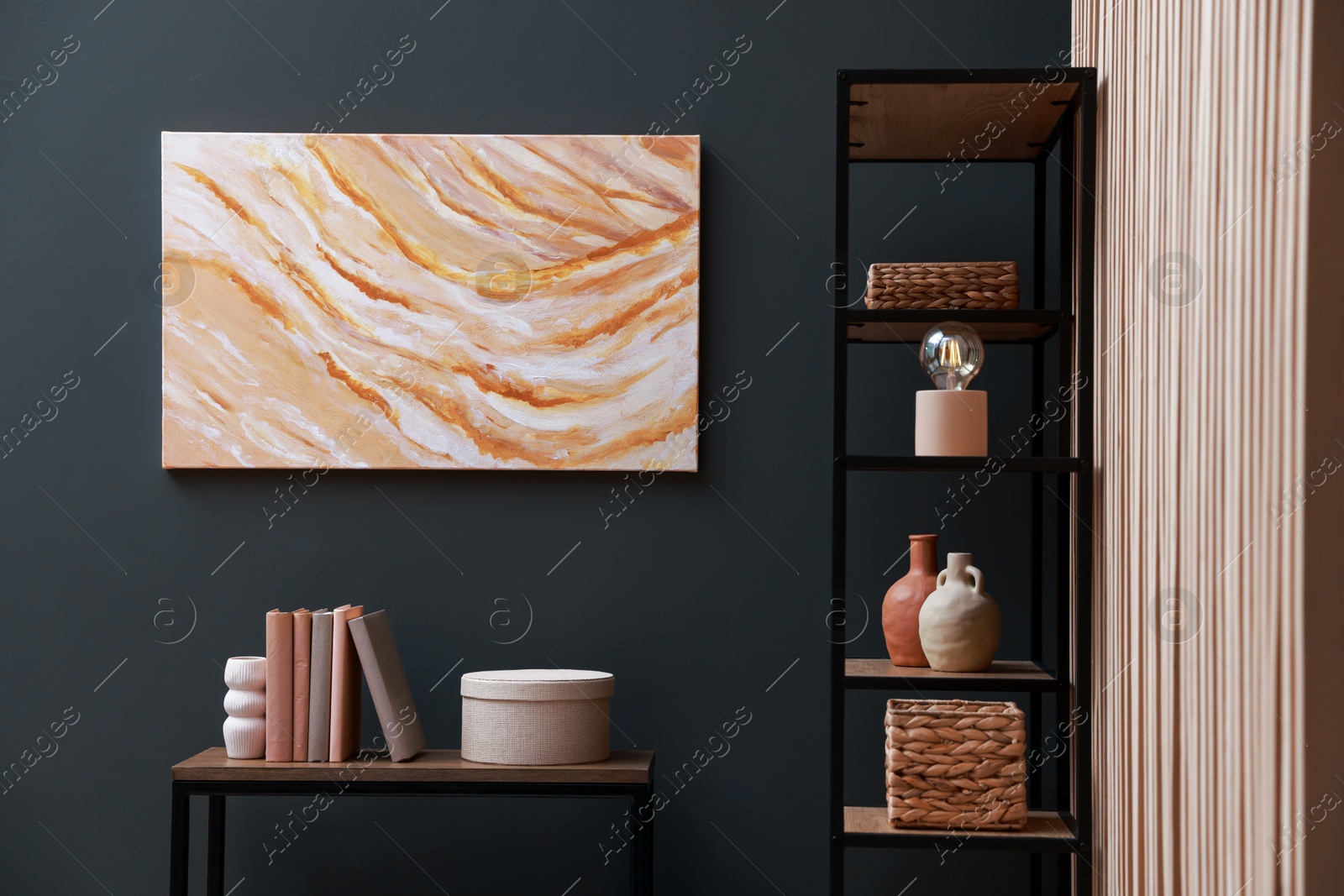 Photo of Console table with decor and shelving unit near grey wall in room. Interior design