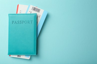 Photo of Passport with tickets on light blue background, top view. Space for text